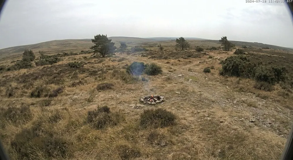 Fire: Generative AI report. Timed capture. Generative AI reports a small contained fire on bare ground with a thin wisp of smoke and no spread into the vegetation. Logged and noted for the warden, no alert.