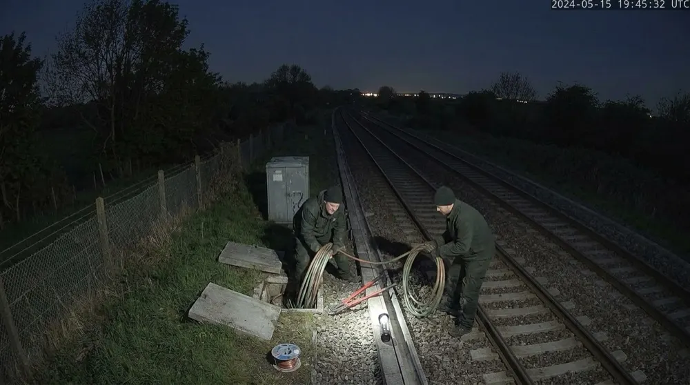 Rail cable theft: Generative AI raises alert. Gen AI confirms suspicious activity — figures without hi-vis at opened troughing pulling cable: theft.